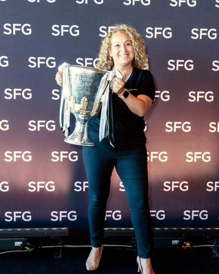 A member of the Jewel Finance team holding a premiership cup at a Specialist Finance Group event